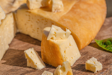 Cubed Swiss cheese pieces arranged on a rustic wooden board in natural light
