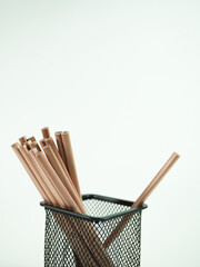 Pencils in a black wire mesh container on white background for school or office projects