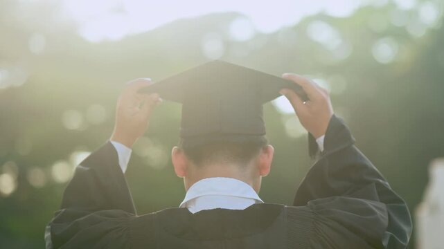 Rear view of graduate adjusting cap, graduation ceremony concept, academic achievement, higher education success, university celebration.