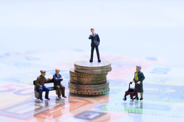 Symbolbild Rentenlücke und Vermögensverteilung – Miniaturfiguren auf Münzen und Euroscheinen