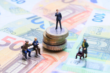 Rentenlücke und Vermögensverteilung – Miniaturfiguren auf Geldscheinen und Münzen