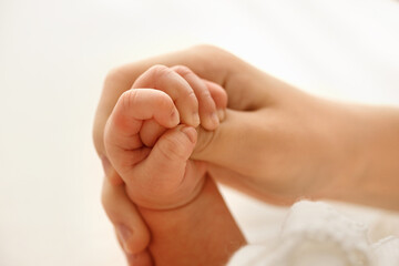 Close-up of a newborn baby tiny hand tightly grasping the mother finger, showing a strong bond, care, and family tenderness on a soft white background.
