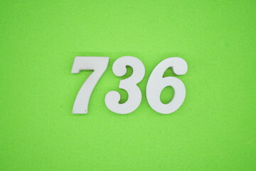 The numbers are made of white painted wood and placed on a green paper background.