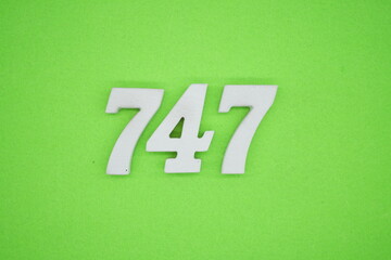 The numbers are made of white painted wood and placed on a green paper background.
