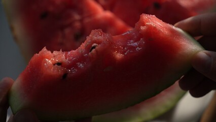 Hands holding bitten slice of watermelon in sunlight