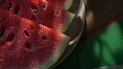 Sliced watermelon on plate with knife on green board