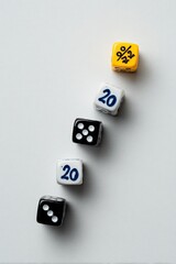 Five dice, various colors, arranged diagonally on a light gray surface.  The dice display numbers and percentages