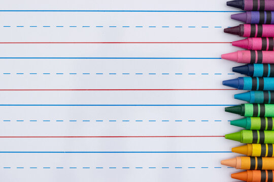 Crayons with ruled loose leaf notebook paper background