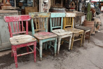 Colorful vintage chairs lined up in a market showcasing rustic charm and character