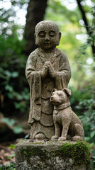 A serene stone statue of a monk praying beside a dog in a lush, green garden environment.