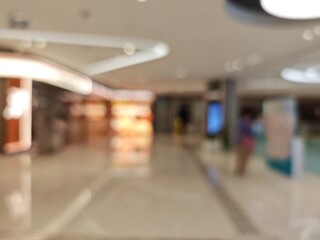 Abstract bokeh image of a shopping mall with blurred lights and indistinct figures.