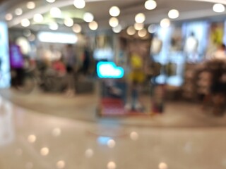 Abstract bokeh image of a bustling shopping mall with blurred lights and indistinct figures.