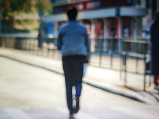Abstract bokeh image of a person walking down a city street, blurred background.