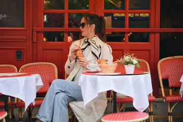 Elegant lady relaxing at outdoor French cafe with pastry and hot drink