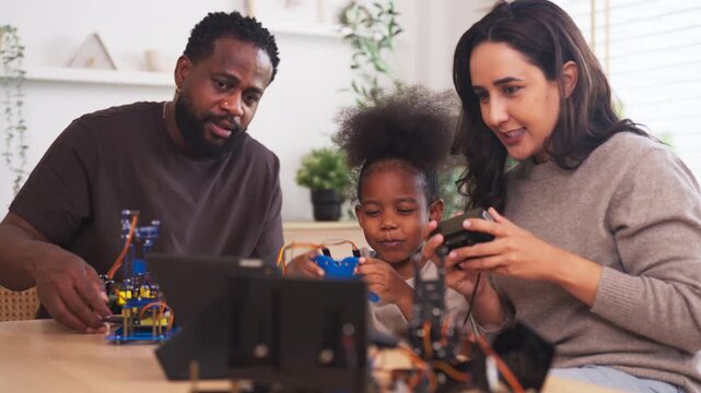 Parents and child assemble a diy robotics kit at home, learning stem skills through play; hands-on coding, engineering and problem solving, modern family education and teamwork.