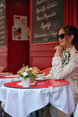 Chic lady relaxes with hot drink at cozy outdoor Paris cafe