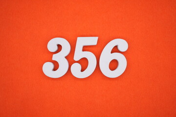 The numbers are made of white painted wood placed on an orange paper background.