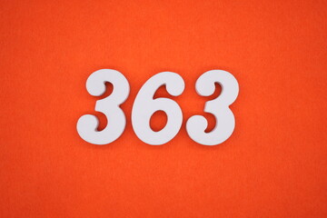 The numbers are made of white painted wood placed on an orange paper background.