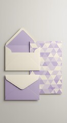 Fototapeta premium Close up of elegant stationery set featuring purple and cream envelopes with a triangle pattern card. Wedding invitation card mockup with copyspace