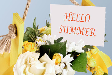 Hello summer words written on a paper note in a bouquet of flowers