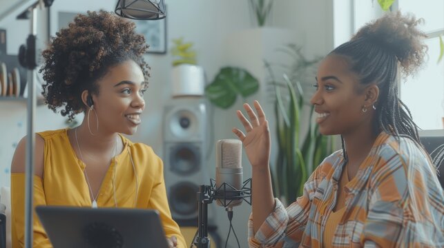 Two women having a conversation while co-hosting an audio broadcast in a home studio. Two female content creators recording an internet podcast for their social media channel.