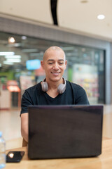 Fototapeta premium Man working on laptop in mall food court, solo digital productivity concept
