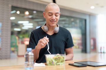 Man eating healthy salad in food court, health and wellness lifestyle