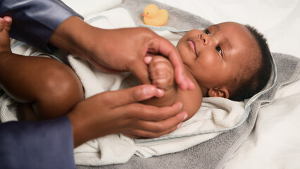 Loving Parent Massaging a Smiling Baby After Bath on a Soft Towel with a Rubber Duck