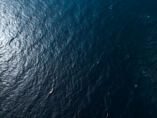 Photo of aerial view of the deep blue sea water surface with sun reflection, creating a mesmerizing texture and pattern, perfect for backgrounds and adding a touch of nature