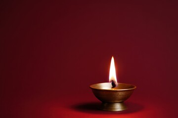 Diwali diya lamp casting warm glow on red background symbolizing light, hope, and spirituality in Hindu festival celebration