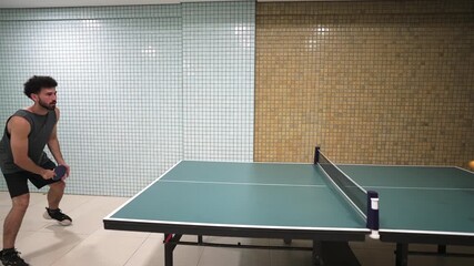 A moment of ping pong serve with the man hitting the ball across the indoor table in several times. - Powered by Adobe