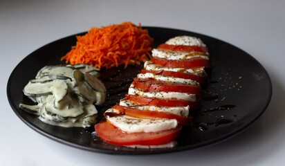Vegetarian dish with a delicious Italian caprese salad, with olive oil and balsamic vinegar; with grated carrot salad and cucumber salad with cream vinaigrette.