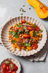 Autumn warm chickpea and roasted pumpkin salad with fresh cherry tomatoes and herbs. Vegan meals