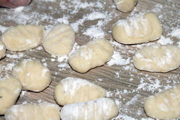 Close up of gnocchi pasta beinng made raw on wooden background covered in flour