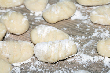 Close up of gnocchi pasta beinng made raw on wooden background covered in flour