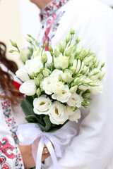 The newlyweds are holding a beautiful wedding bouquet in their hands.