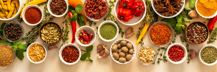 Variety of vibrant spices and dried herbs arranged on a beige backdrop, essential for culinary...