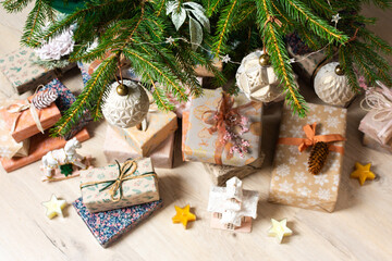 Beautifully wrapped gift boxes in natural colors sit neatly under a Christmas tree adorned with ornaments, creating a warm and serene holiday vibe