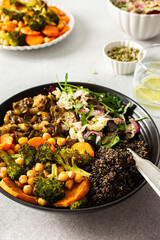 A balanced breakfast bowl with black quinoa, avocado, roast chicken, and sweet potatoes, topped with a fresh cabbage and radish salad