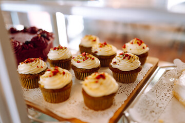 Fresh and flavorful desserts are tempting under the glass dome of this cozy bakery. Cozy atmosphere with fragrant cinnamon buns, cupcakes and muffins in the coffee shop. Dessert and food concept.