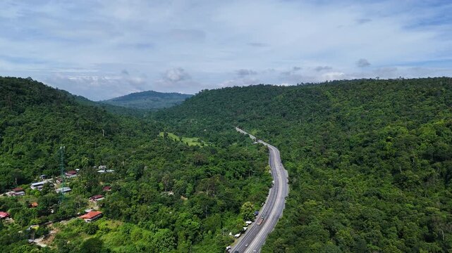 Drone footage of the aerial view of a winding road cutting through lush green forest. Scenic highway number 304 in Thailand links the Bangkok area to Nakhon Ratchasima in the northeastern region