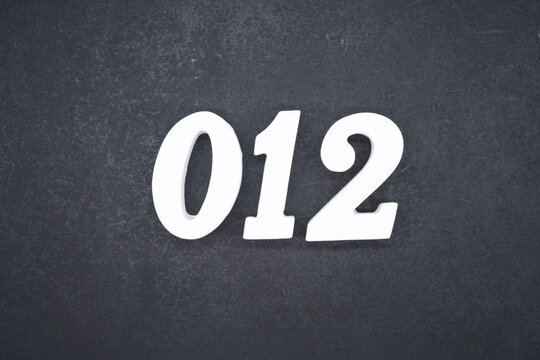 The numbers are made of white painted wood and placed on a black plastic background.