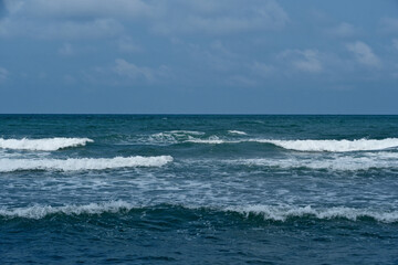 Seascape with waves on the Black Sea coast in Georgia. Waves on the seashore. Blue sky with white clouds.