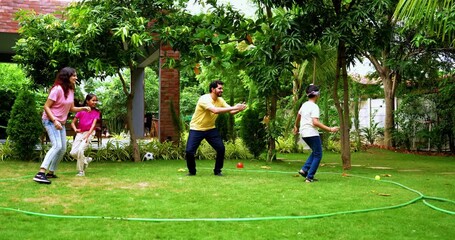 Indian family playing blind fold game in home garden, spending quality fun time together enjoying outdoor sports, parents and children laughing, running, and bonding through playful backyard activity