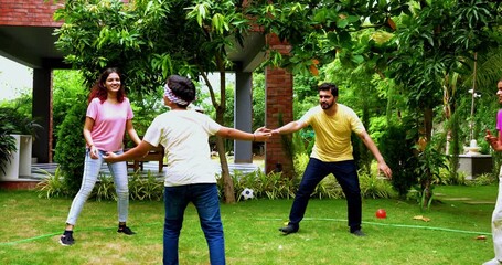 Indian family playing blind fold game in home garden, spending quality fun time together enjoying outdoor sports, parents and children laughing, running, and bonding through playful backyard activity