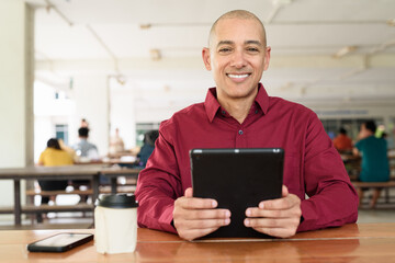 Man using digital tablet computer device at outdoor cafe restaurant table in urban academic setting