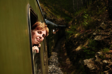 Woman looking out of a vintage train window in the mountains of Mokra Gora, enjoying the scenic ride. Sargan Eight - a popular tourist destination in Serbia.