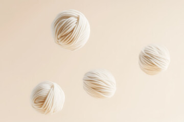 Floating Wool Spheres: Cozy Crafting Essentials. Four balls of white wool yarn hover against a soft background, perfect for knitting and creative projects.