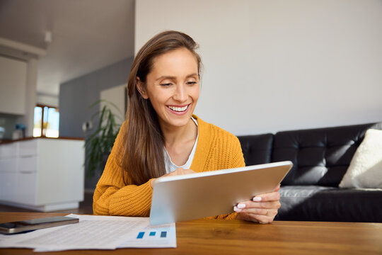 Woman doing paperwork at home using digital tablet