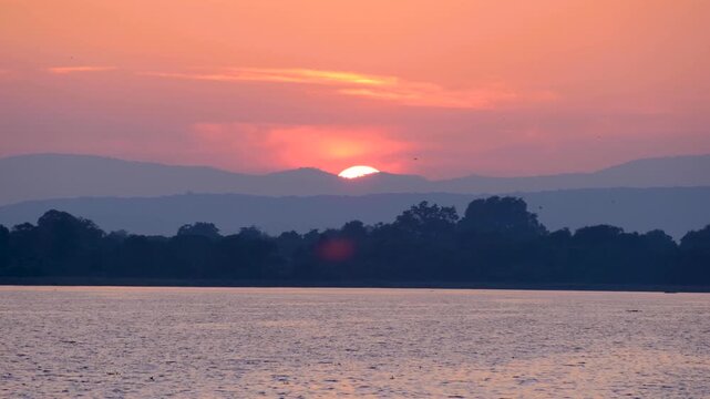 Burning red sun setting beyond the horizon overlooking Parakrama Samudra Lake in Polonnaruwa Sri Lanka